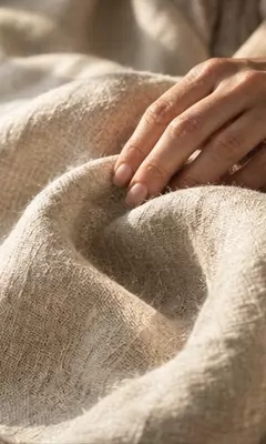 Mano che accarezza un tessuto di puro lino